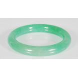 A 20th Century Chinese green jade bangle of round form. Interior diameter 5.5 cm. Measures 7.5 cm