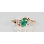 An 9ct yellow gold ladies dress ring set with a central faceted cut oval emerald flanked by clusters