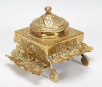 A Victorian 19th century brass desk top single inkwell. Raised on c-scroll feet with rococo cast