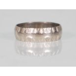 A hallmarked 18ct white gold band ring having engraved decoration to the borders. Hallmarked