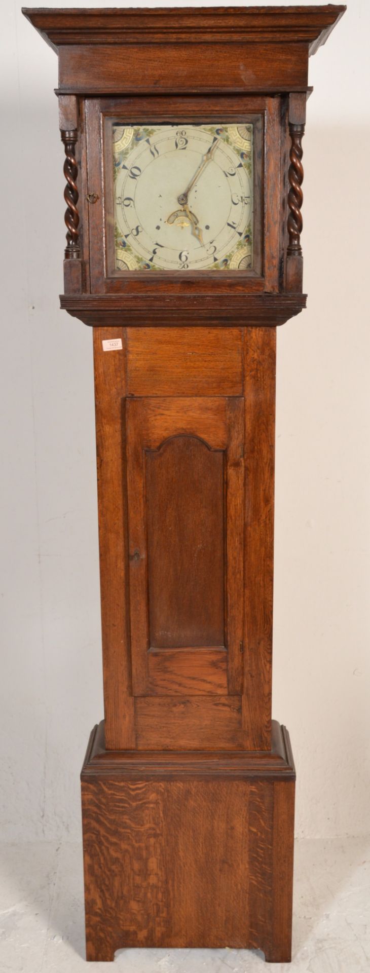 An early 20th Century oak long cased grandfather clock having a square face with hand enamelled dial