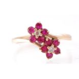 A 9ct gold ruby and diamond double flower head ring. Each flower with ruby petals and diamond