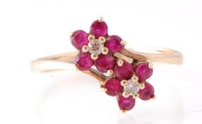 A 9ct gold ruby and diamond double flower head ring. Each flower with ruby petals and diamond