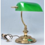 A 20th century bankers lamp having a brass body with a curved neck and rotating green glass shade.