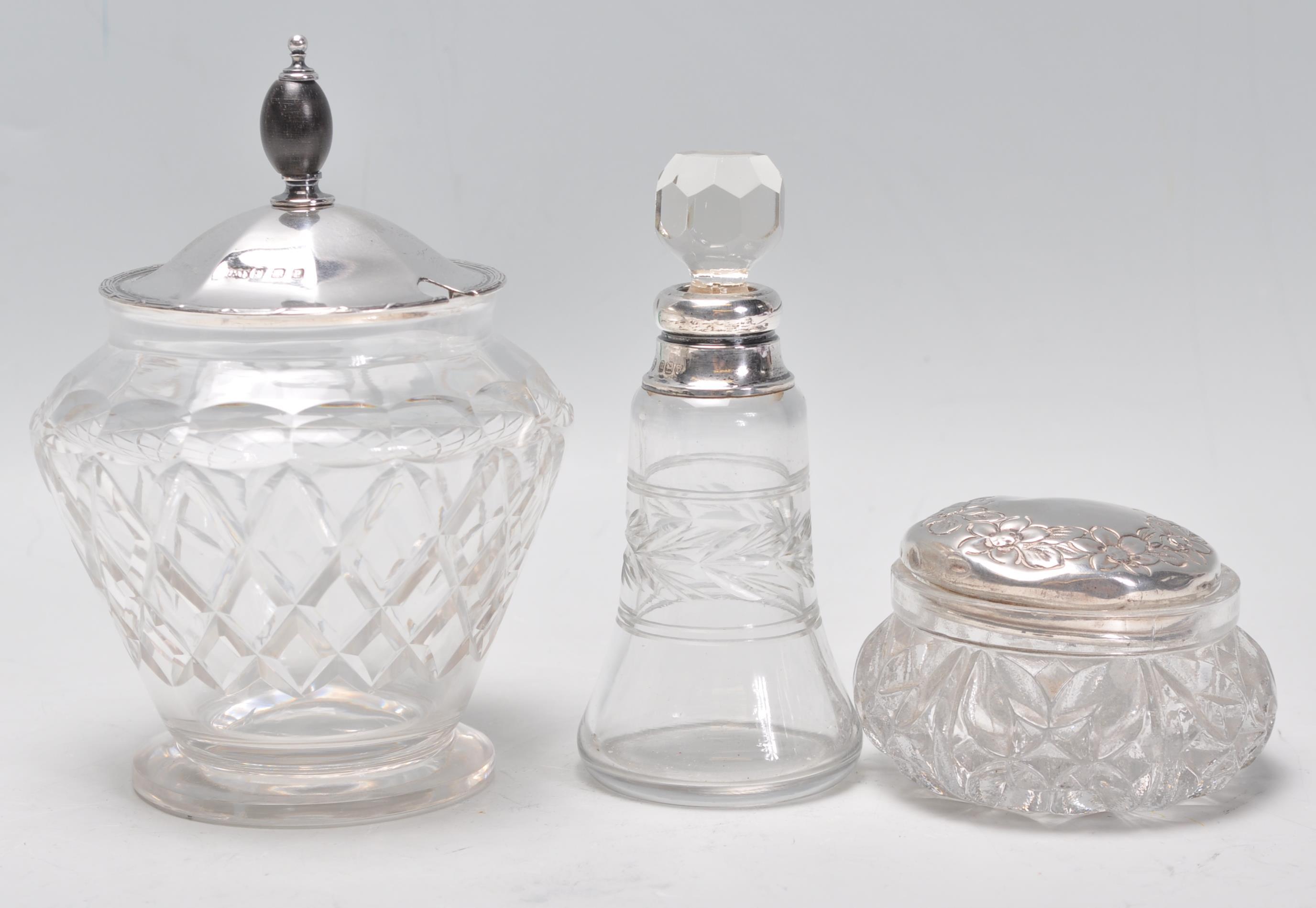 A group of three cut glass and silver items to include a jam pot having a silver hallmarked lid with