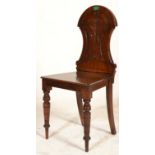 A 19th Century mahogany hall chair having a domed back with a carved flower and shaped panels