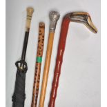 A group of three walking sticks to include a faux bamboo cane with a carved duck head handle, a