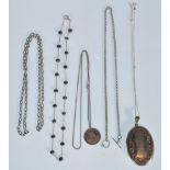 A collection of silver necklaces to include a large silver locket of oval form, a fine chain