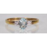 An 18ct yellow gold ladies dress ring prong set with an oval cut blue stone flanked by round cut