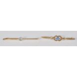 A stamped 15ct gold bar brooch set with a central round faceted cut blue stone. Weighs 2.1g.