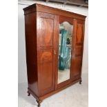 An Edwardian mahogany ebony line inlaid triple wardrobe. Raised on a plinth base with double section