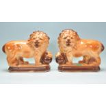 A matching pair of early 20th Century Staffordshire ceramic fire dogs in the form of lions having