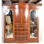 An Edwardian mahogany bow front marquetry inlaid triple wardrobe compactum. Raised on a plinth