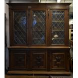 A large and impressive oak and leaded glass library bookcase cabinet. Raised on bun feet with flared