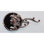 A sterling silver and onyx art nouveau style brooch in the form of a lady with a ruby set scarf.