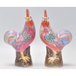 A pair of 20th Century Chinese ceramic cockerel figurines having polychrome glazed feathers, each