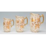 A set of three vintage early 20th Century jugs of graduating sizes having shaped gilt handles with