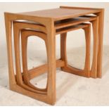 A 1970's G-Plan oak quadrille pattern nest of tables being raised on squared legs with shaped