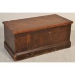 A 19th Century pine blanket box chest being raised on a plinth base with hinged lid atop opening