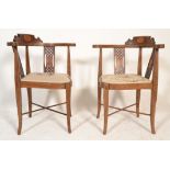 A pair of Edwardian mahogany and marquetry inlaid corner chairs being raised on square tapering legs