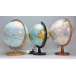 A collection of vintage 20th century desk top world globes, each of spherical form and raised on