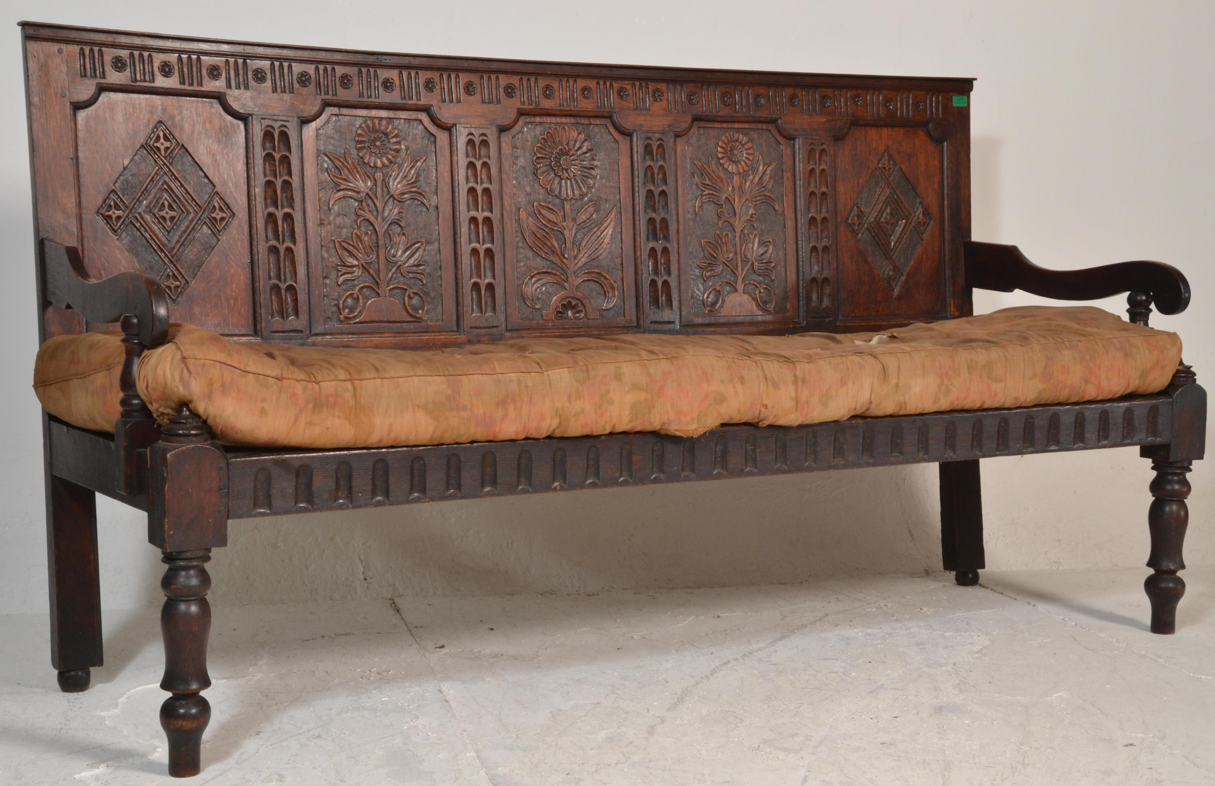 An 18th century large carved West country oak hall settle bench. Raised on turned legs with