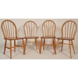 A  matched set of 4 20th century Ercol beech and elm wood Windsor pattern dining chairs being raised