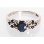 A stamped 9ct white gold ring set with an oval cut blue stone with round cut blue and white accent
