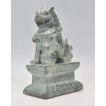 A 20th Century Chinese cast metal temple foo / fu temple dog modelled seated on a plinth base with a