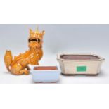 A Chinese ceramic figure of a Qilin / mythical beast modelled sitting having an orange glaze