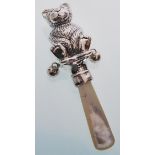 A sterling silver babies rattle in the form of a teddy bear with a mother of pearl handle. Gross