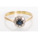 A stamped 18ct gold ladies ring set with a round cut sapphire with a halo of round cut diamonds.