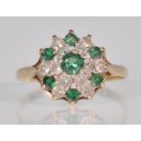 A hallmarked 9ct yellow gold cluster ring set with white and green round faceted cut stones on a