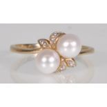 A hallmarked 9ct yellow gold ladies ring set with two pearls and diamond accent stones on a