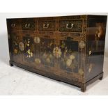 A Chinese black lacquered sideboard credenza being raised on squared legs with short drawers over
