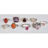 A collection of 9 silver rings to include a knot design ring set with an oval cut purple stone,
