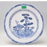 A 19th Century Chinese blue and white wall charger plate being hand painted with a pine tree and