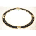 Harrison & Gil - A good large oval gilt and ebonised wall mirror having a large central beveled