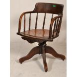 An Edwardian beech wood Industrial office factory swivel armchair raised on a four point base with