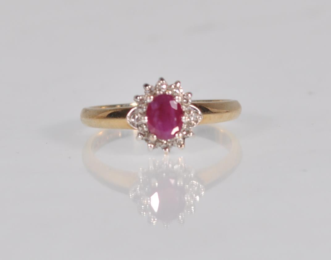 A hallmarked 9ct gold diamond and garnet flower head ring having a central faceted red stone with