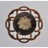 A vintage hallmarked 9ct gold brooch having a round cut smokey brown stone within a pierced