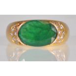 An 18ct gold ladies dress ring set with an oval cut emerald with stepped diamond accent stones to