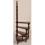 A set of antique style mahogany library steps of shaped form rising up through to a turned column