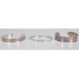 A group of three stamped 925 silver bangle bracelets to include a cuff bangle with raised borders, a