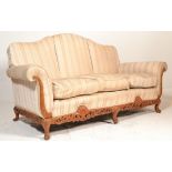 A large 20th century antique style camel back sofa settee being raised on squared legs with