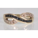 A decorative English hallmarked 9ct yellow gold crossover ring set with square cut black stones