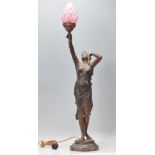 An early 20th Century Art Nouveau table lamp in the form of a female figure holding a torch aloft,