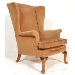 A mid 20th century Parker Knolll wing back armchair raised on a beech wood show frame with