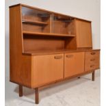 A mid century teak wood Danish influence highboard - sideboard credenza being raised on tapering