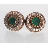 A pair of sterling silver earrings set with round cut green stones with a halo of white accent